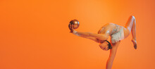 One Professional Rhythmic Gymnastics Artist Training With Golden Color Ball Isolated On Orange Background. Concept Of Sport, Action, Aspiration, Competition