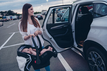 Canvas Print - Photo of sweet cheerful mom small daughter wear casual outfits open door putting car seat inside automobile vehicle