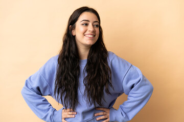 Wall Mural - Young caucasian woman over isolated background posing with arms at hip and smiling