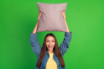 Wall Mural - Photo of pretty satisfied lady hands hold raise pillow above head isolated on green color background
