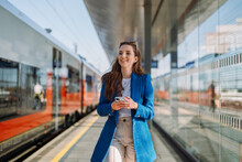 Young Woman Holding Mobile In A Train Station. Commuting To Work. Public Transport Concept.
