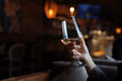 © Lavsketch - Female hand with french manicure holding a glass with wine on naturally blurred background. Woman in restaraunt. Luxury pasttime, celebration concept.