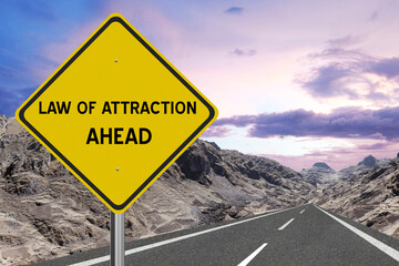 Yellow highway sign with the words Law of Attraction and a metaphoric road leading to future success.