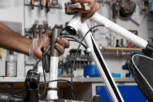 Experienced Bicycle Repairman In Protective Gloves Disassembles Steering Column Of The Bike For Cleaning And Lubrication. Seasonal Maintenance Of Bicycles By Technicians In A Professional Repair Shop