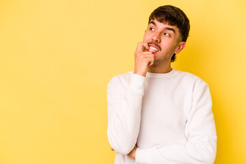 Wall Mural - Young caucasian man isolated on yellow background relaxed thinking about something looking at a copy space.