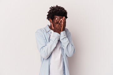 Young african american man isolated on white background  blink at the camera through fingers, embarrassed covering face.