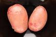 © Oleksandr - Two organic pink potatoes on a black ceramic dish, close-up, top view.