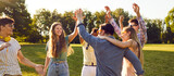 Fototapeta  - Bunch of happy young friends all together having fun on warm sunny day in summer park. Diverse group of cheerful joyful positive people standing on green lawn, smiling and giving each other high five