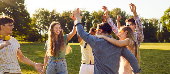 bunch of happy young friends all together having fun on warm sunny day in summer park. diverse group