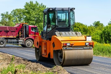 Road roller for road construction travels along road and compacts asphalt pavement laid by asphalt paver. New asphalt pavement on road to settlement. Close-up. Krasnodar, Russia - May 29.