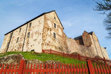 Wall Mural - Medieval Kastelholm Castle behind red wooden fence in Åland Islands, Finland, on a sunny day in the summer.