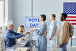 © Seventyfour - Side view at diverse group of people in line at voting station on election day, copy space