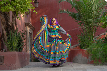 Wall Mural - Young Mexican woman in a traditional folklore dress of many colors, traditional dancer.