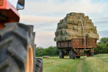 Selective Focus Of Tractor Trailer Heavily Loaded With Hay Bales In The Countryside. Warm Sunset Light.