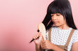 © sorapop - Asian little kid 10 years old hold comb brushing her unruly she touching her long black hair at studio shot isolated on pink background, Happy child girl with a hairbrush, Hair care concept
