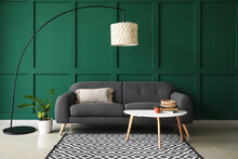 Comfortable Sofa With Table And And Modern Lamp Near Green Wall