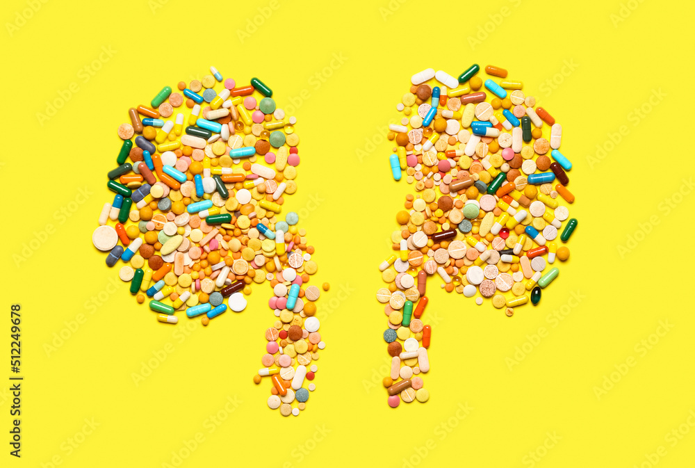 Kidneys made of pills on yellow background