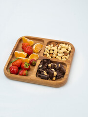 Wall Mural - wooden bowl filled with fruits, nuts, strawberries, chocolate on a white background. Picnic in nature