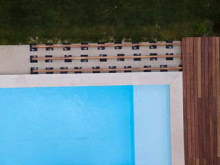 Wall Mural - Drone flight over beautiful green garden with pool and the wooden terrace of the pool is currently in progress