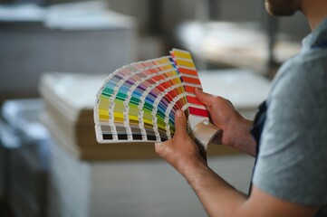 Man working in printing house with paper and paints