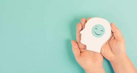 Holding a head with a smiling face in the hands, mental health concept, positive mindset, support and evaluation symbol