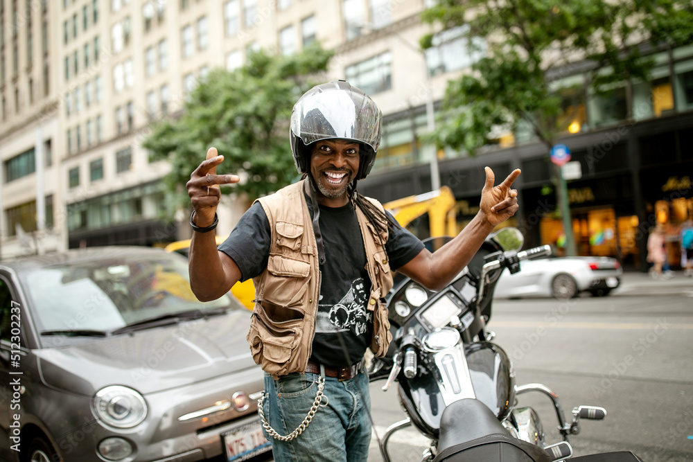 Photo Stock Cute biker wear helmet, stay near bike, spread his arms in greeting. Afro American mature motorcyclist smile at camera, motorbike on the street on Manhattan. | Adobe Stock Photo Stock Cute biker wear helmet, stay near bike, spread his arms in greeting. Afro American mature motorcyclist smile at camera, motorbike on the street on Manhattan. | Adobe Stock
