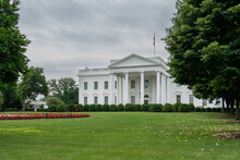 Front View Of The White House And Green Grass With Cloudy Skies