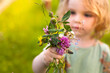 Kind mit selbst gepflückten Blumen. Kind pflückt Blumen in Blumenwiese.