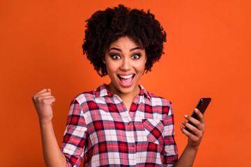 Canvas Print - Portrait of delighted person raise fist celebrate follow hold phone isolated on orange color background