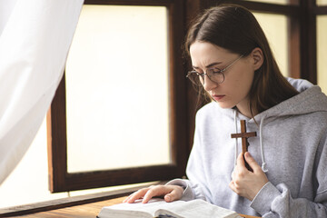 Wall Mural - The girl reads the Bible and prays. Prayer process. Faith and hope. The process of praying to God. Believer.