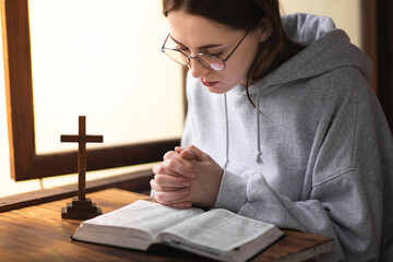 Wall Mural - The girl reads the Bible and prays. Prayer process. Faith and hope. The process of praying to God. Believer.