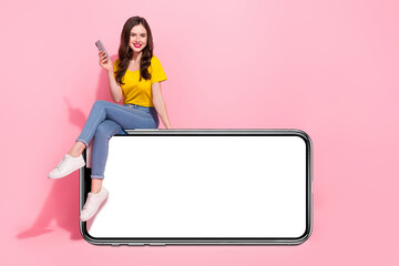 Full size photo of cheerful charming lady sit empty space blank hold telephone isolated on pink color background