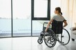 © Serhii - Young woman in wheelchair at home in living room.