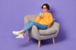 © deagreez - Portrait of attractive cheerful girl sitting using device communicating post video isolated over violet lilac color background