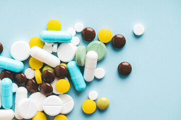 various pills on blue background, top view.