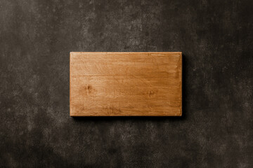 Wall Mural - Wooden chopping board over dark stone kitchen background. Top view copy space
