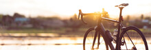 Road Bike Parked On A Beautiful Road Sunset, Warm Light With Copy Space.