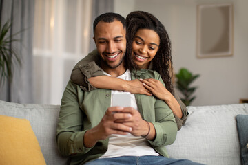 Wall Mural - Happy African American Couple Using Mobile Phone At Home