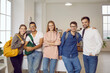 © Studio Romantic - International education. Group portrait of happy and positive multiracial university friends posing in classroom. Five smart international students in casual clothes smile together and look at camera.
