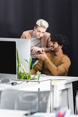 happy indian designer pointing at computer monitor near advertising manager.