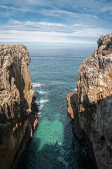 calm ocean between two cliffs cliffs under blue cloudy skies
