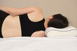 A woman lies on an orthopedic pillow, view from behind. Correct posture and position of the spine during sleep on the side.