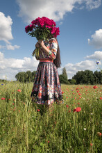 Girl In Floral Dress Standing In A Poppy Field Holding Bouquet Of Pink Roses