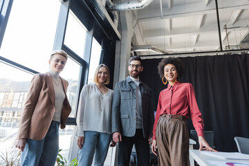 Wall Mural - low angle view of successful interracial business people looking at camera in advertising agency.