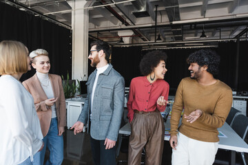 Wall Mural - cheerful multiethnic business people talking and gesturing in advertising agency.