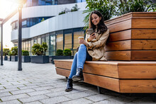 Woman Sitting On Bench And Using Phone