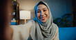 Close-up Asia muslim woman in hijab with casual sitting on sofa use smartphone video conference selfie look at camera with boyfriend on living room in home at night. Girl Islam lifestyle concept.