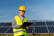 © NFstock - Electricity engineer man holding clip board and taking notes while looking at solar panels. Green energy and ecology concept