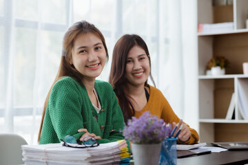 Two women sitting through white papers and talking, two business women discussing brainstorming and planning operations, form a partnership to form a startup company. Management of startup company.