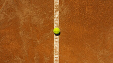  A Yellow Tennis Ball Lies On The Clay Court.